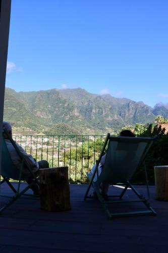 two people sitting in chairs on a porch with mountains at Villa with Mountain view, São Vicente, Madeira in São Vicente