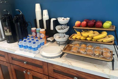a counter with a bunch of food and drinks and fruit at Super 8 by Wyndham Oceanside Downtown in Oceanside