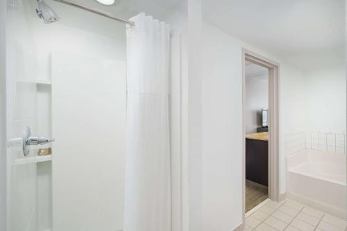 a white bathroom with a shower curtain and a tub at Country Inn & Suites by Radisson, Orlando Airport, FL in Orlando
