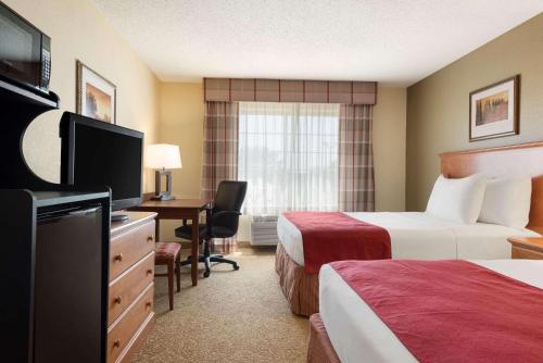 a hotel room with two beds and a desk with a television at Country Inn & Suites by Radisson, Davenport - Quad Cities in Davenport