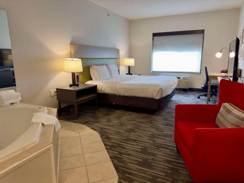 a hotel room with a bed and a red couch at Country Inn & Suites by Radisson, Queensbury - Lake George , NY in Lake George