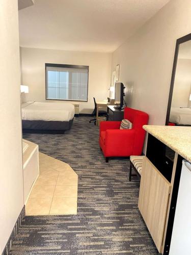 a hotel room with a bed and a red chair at Country Inn & Suites by Radisson, Queensbury - Lake George , NY in Lake George