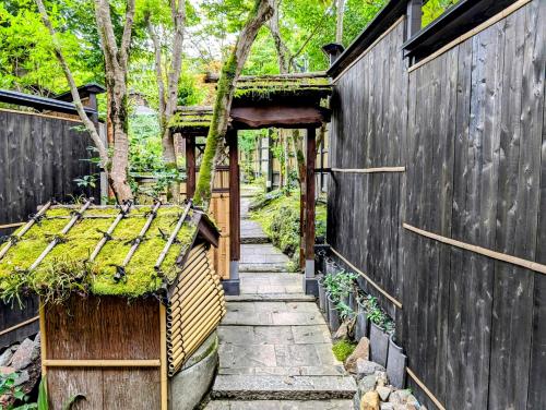 a garden with a wooden fence and a pathway at Ryoso Yufuin Yamadaya in Yufuin