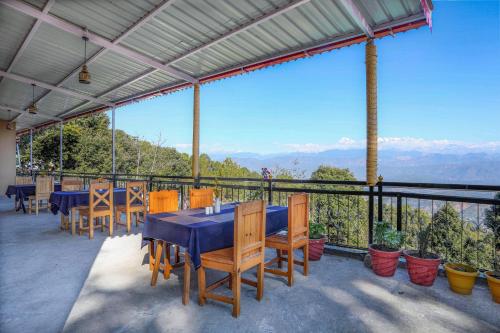 a table and chairs on a balcony with a view of mountains at Blossom Hideaway Kausani in Kausani