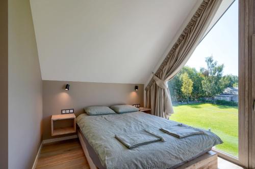 a bedroom with a bed and a large window at Jesionowa 3 Domki in Rowy