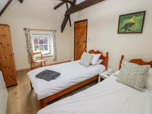 a bedroom with two beds and a window at 2 Cheriton Cottages in Pembroke