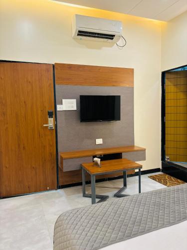 a living room with a tv and a wooden table at Hotel Legend's Aurangabad in Aurangabad