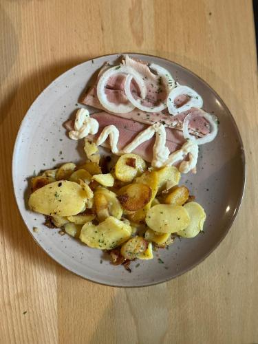 a plate of food with onions and potatoes on a table at Winzergasthof zum Kellerstübchen in Mehring