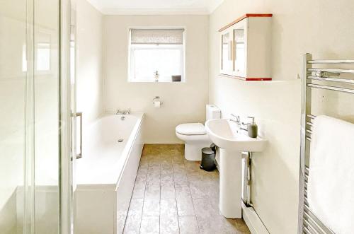 a bathroom with a toilet and a tub and a sink at PLEASANT View Impressive Home In Stunning Rhondda Valley By Staystaycations in Pontypridd