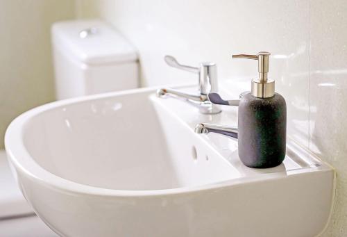 a soap dispenser sitting on a sink in a bathroom at PLEASANT View Impressive Home In Stunning Rhondda Valley By Staystaycations in Pontypridd