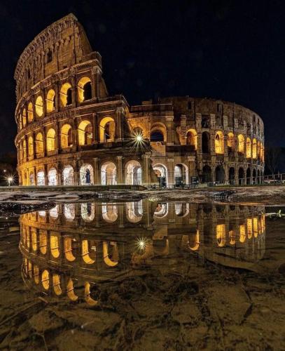 a building with its reflection in the water at night at Aniene Home Roma in Rome