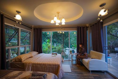a woman sitting in a room with a bed and a couch at ปางสูงเฮาส์ บ้าน Coffee Love in Ban Pang Bo Hu Bon