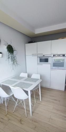 a white kitchen with a table and white cabinets at Stylowy Apartament z ogrodem in Gorenice