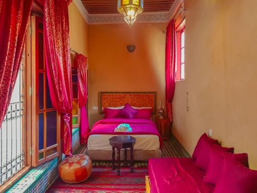 a bedroom with a pink bed and red curtains at RIAD LALJ Fes in Fès