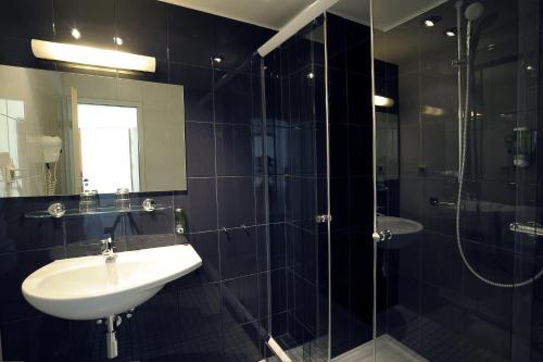 a black tiled bathroom with a sink and a shower at Hotel Ludwig van Beethoven in Berlin