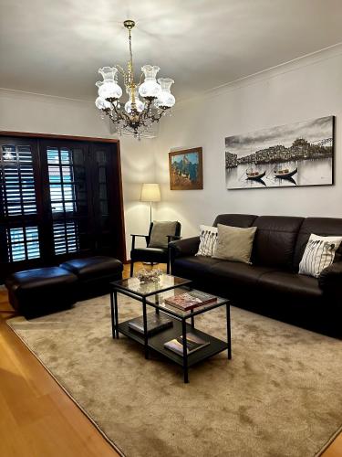 ein Wohnzimmer mit einem schwarzen Sofa und einem Kronleuchter in der Unterkunft Central Home in Arouca