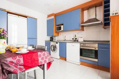 a kitchen with blue cabinets and a table with a red table cloth at Pasaje de los Giles in Zaragoza