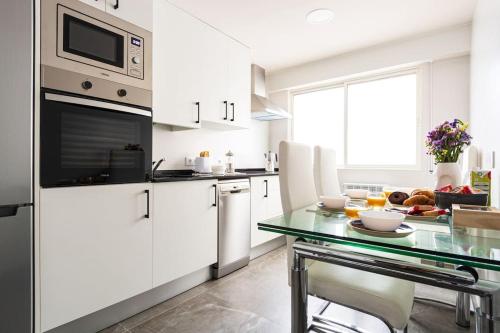 een keuken met witte kasten en een glazen tafel bij Prudencio 36 in Zaragoza