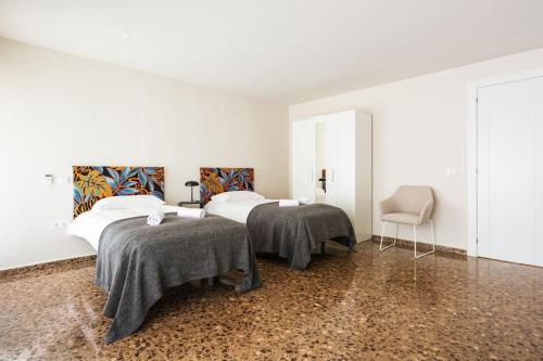 een slaapkamer met 2 bedden en een stoel bij Prudencio 36 in Zaragoza