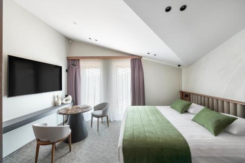 a hotel room with a large bed and a flat screen tv at Harmony Birštonas in Birštonas