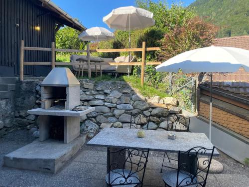 a patio with a grill and a table and umbrella at Charming Alpine Retreat By Apartments Capricorn in Gsteigwiler