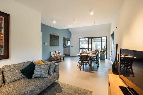 a living room with a couch and a dining room at vakantiehuis Cerise, Luxueus genieten in de Leiestreek in Deinze