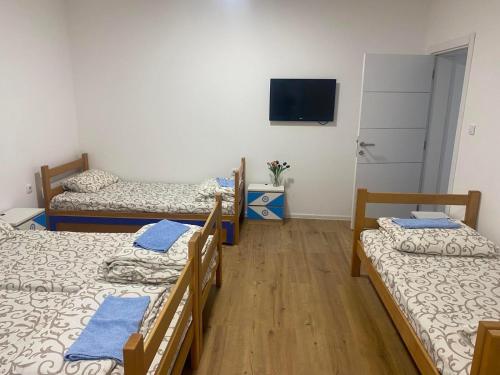 a room with three beds and a flat screen tv at Dušanov konak in Vrbas