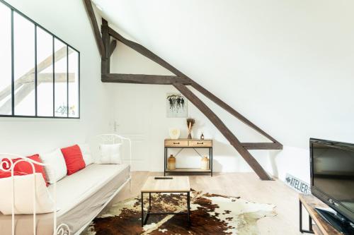 un salon avec un canapé blanc et une télévision dans l'établissement Le comble du bonheur, à Cinqueux