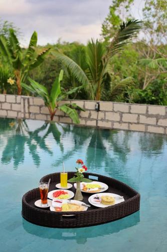 MT Penida Bungalow في نوسا بينيدا: طاولة مع طعام ومشروبات فوق مسبح