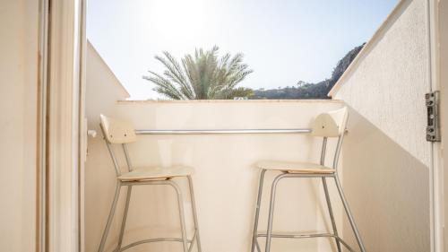 two stools in front of a window with a plant at Blue Star Hotel in Oludeniz