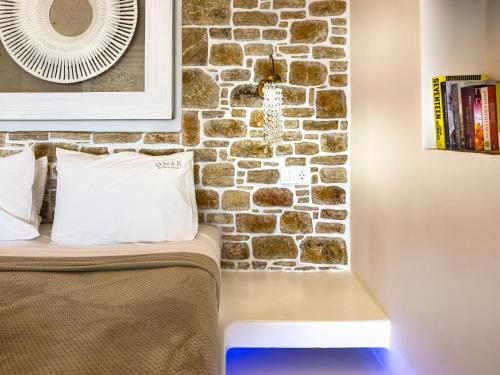 a room with a brick wall and a bed with a pillow at Onar Suites & Villas in Karavostasi