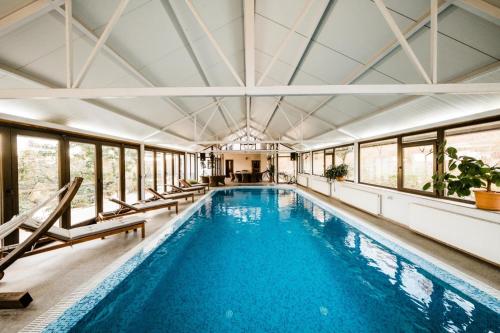 an indoor swimming pool with chairs and a swimming pool at Hidden Hills Villa in Ţipăreşti