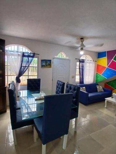 a living room with a glass table and blue chairs at Casa con piscina EN BOCA CHICA in Boca Chica