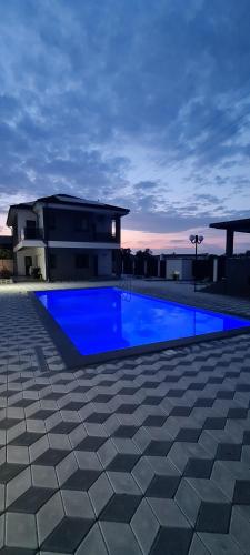 a large blue swimming pool in front of a house at Grey House in Bucharest
