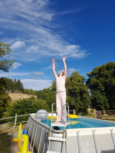 une femme est debout sur une plate-forme à côté d'une piscine dans l'établissement La Tourette with private pool and nearby swimming lake, à Saint-Genès-la-Tourette