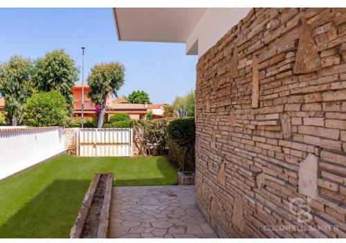 a brick wall with a bench in a yard at MDF Monolocale a Fregene 100 mt dal mare in Fregene