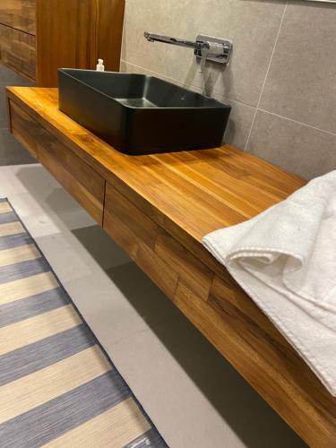 a black sink on a wooden counter in a bathroom at Immaculate apartment in Umm Uthainah