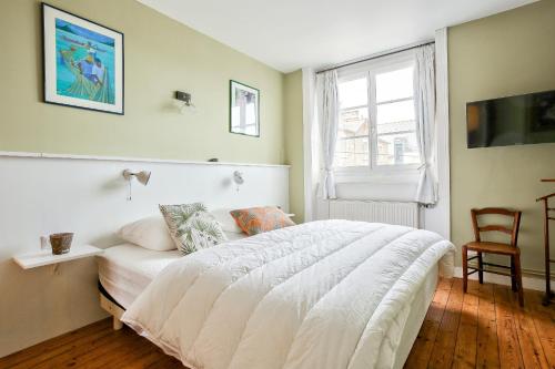 une chambre avec un lit blanc et une fenêtre dans l'établissement 50m de la plage du Prieuré - Maison de ville pour 6, à Dinard