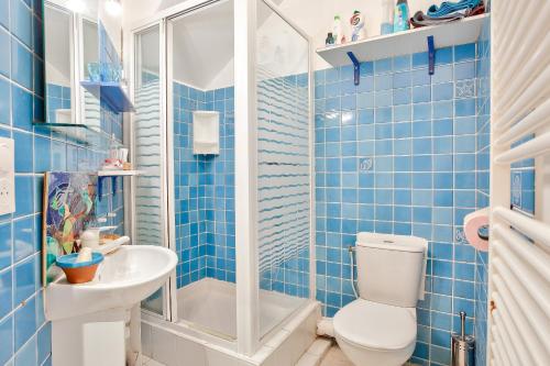 La salle de bains est pourvue de carrelage bleu, de toilettes et d'un lavabo. dans l'établissement 50m de la plage du Prieuré - Maison de ville pour 6, à Dinard