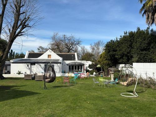 a yard with a group of chairs and swings at Greyton Toad Hall exclusive use up to 18 and by supplement up to 22 with massive pool and hot tub and sometimes we rent individual rooms in Greyton