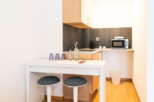 a small kitchen with a white table and two stools at Hôtel Restaurant La Croix Verte Vich in Vich