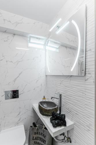 a white bathroom with a sink and a mirror at AcroLofts M62 in Athens