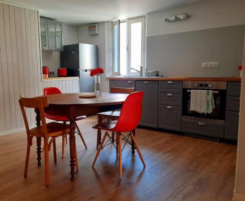 una cucina con un tavolo di legno e sedie rosse di Duplex dans le coeur historique de Guérande a Guérande
