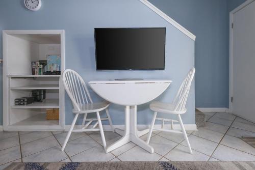 a white table and two chairs in a room with a tv at Sugar Beach 353 in Gulf Shores
