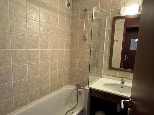 une salle de bain avec une baignoire, un lavabo et un miroir dans l'établissement Appartement au pied des pistes avec balcon et casier à skis - FR-1-181-2076, à La Plagne Tarentaise