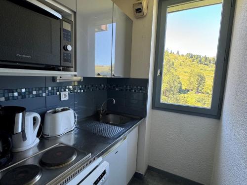 une petite cuisine avec un évier et une fenêtre dans l'établissement Appartement fonctionnel · Skis aux pieds · Balcon - FR-1-181-2167, à La Plagne Tarentaise