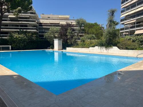 une grande piscine bleue devant un immeuble dans l'établissement La Perle de Juan les Pins, à Juan-les-Pins