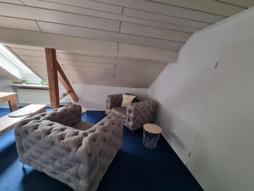 a living room with two chairs in a attic at Ferienwohnung Familie Kleinbauer in Wirsberg