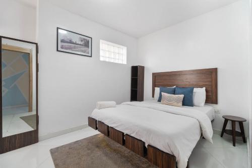 a white bedroom with a large bed and a mirror at Sigma Base Apartments in Lagos