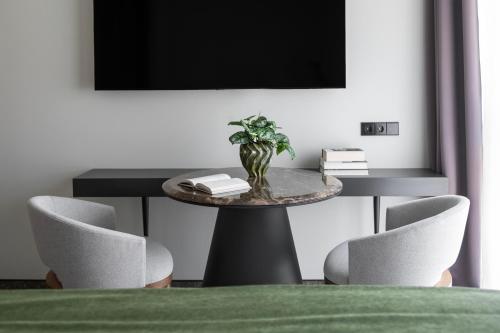 a table with chairs and a television on a wall at Harmony Birštonas in Birštonas